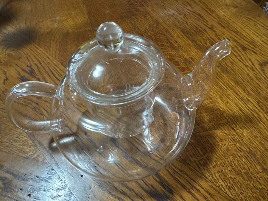 The glass teapot seen from above on a wooden table, spout and handle in view. Photographed by J***r, a verified buyer